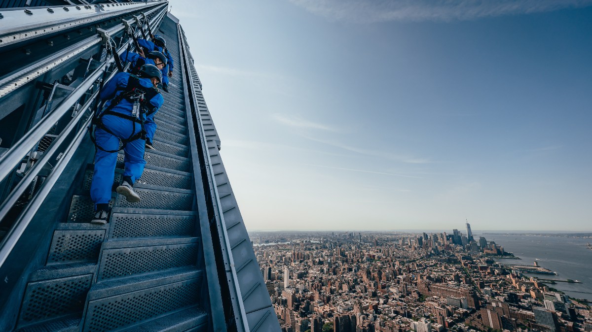 Presos em cabos de segurança, visitantes sobem escadas e param em plataformas na lateral externa de um dos maiores edifícios de Nova York