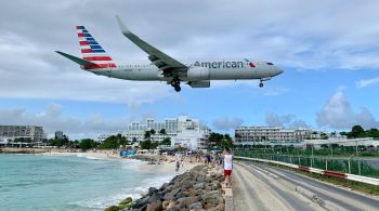 Colada ao aeroporto de St. Maarten, praia Maho é atração mundialmente famosa onde rajadas de ventos dos motores a jato empurram turistas na areia; bares e hotéis luxuosos se beneficiam dos visuais instagramáveis