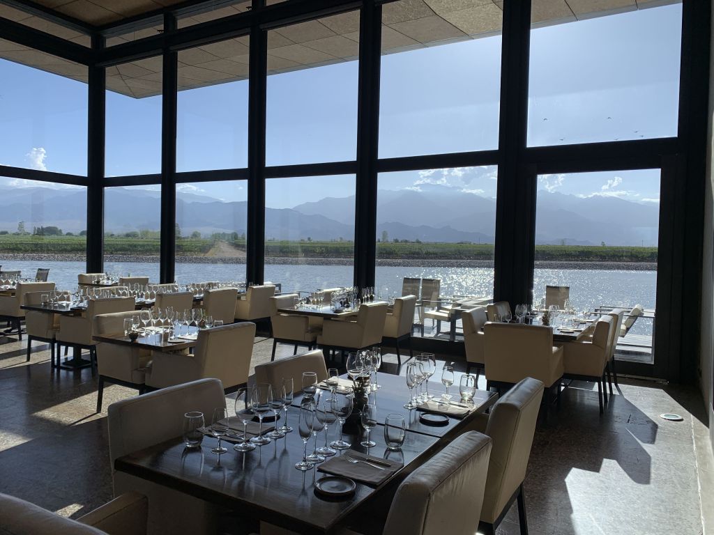 Ambiente interno do restaurante da Alfa Crux, o Crux Cocina, com vistas para vinhedos, lago e a Cordilheira