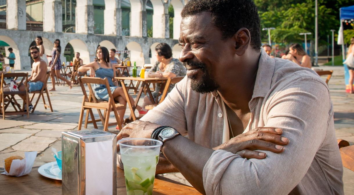 Seu Jorge em cena de "How To Be a Carioca" com os Arcos da Lapa ao fundo, no Centro do Rio