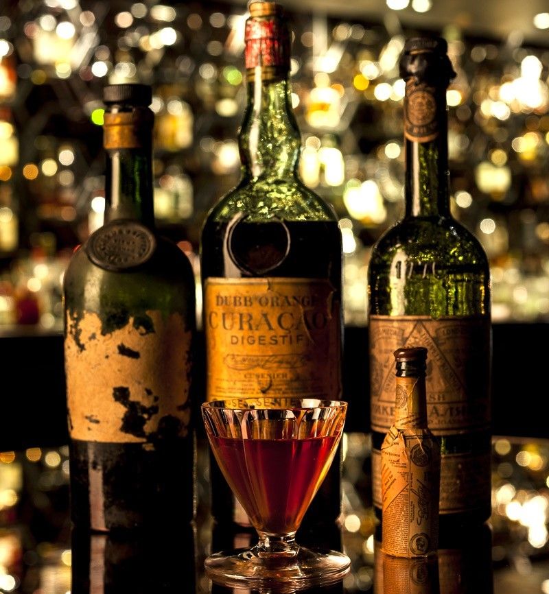 Coquetel Salvatore's Legacy junto de garrafas de destilados vintage