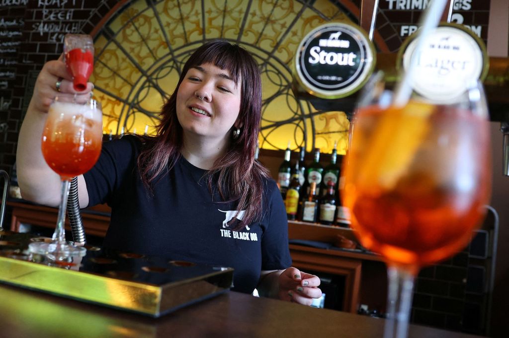 Uma funcionária do pub The Black Dog é retratada fazendo um coquetel 'Aperol Spritz (Taylor’s Version)'