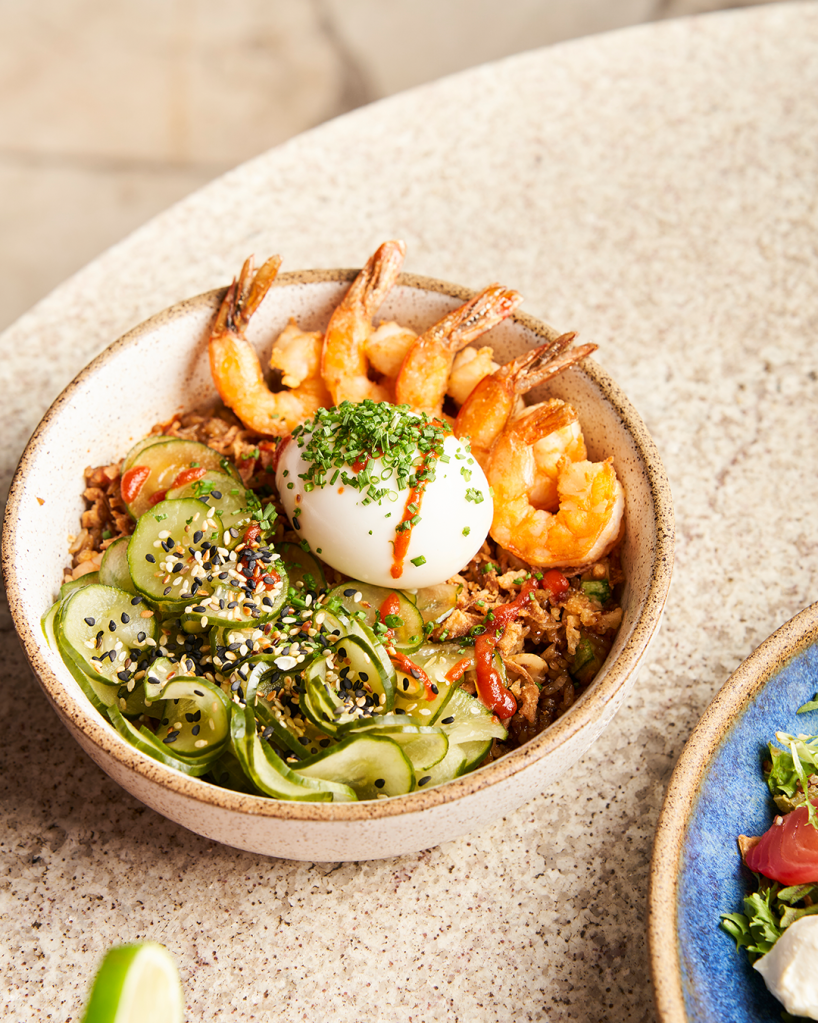 Nasi Goreng (R$79), arroz jasmim, servido com legumes e amendoim puxados na wok com molho oriental, alho e cebola fritos, camarões, ovo mollet, sunomono, gergelim, pimenta sriracha, molho teriyaki e cebolete