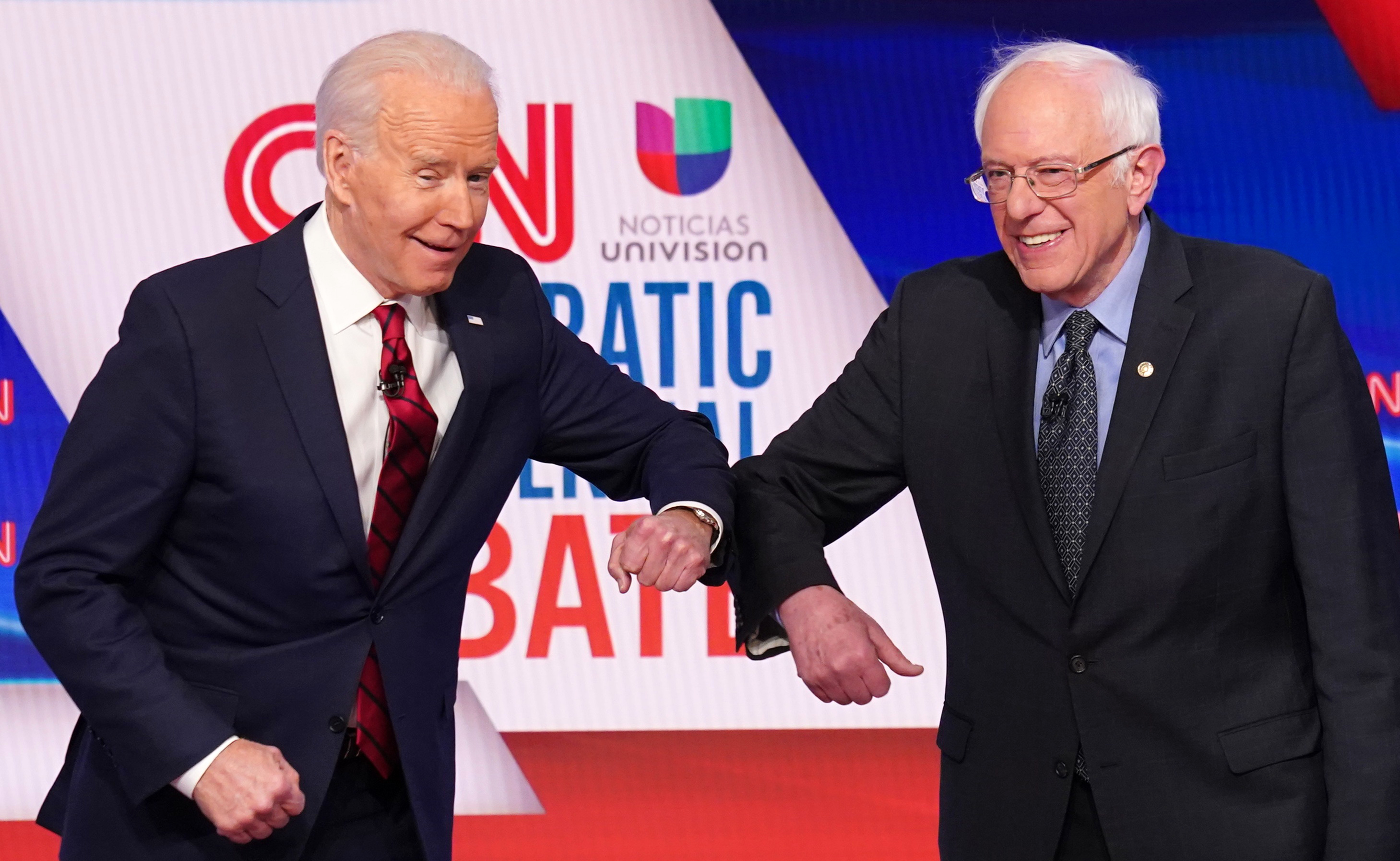 Joe Biden e Bernie Sanders se cumprimentam usando os cotovelos