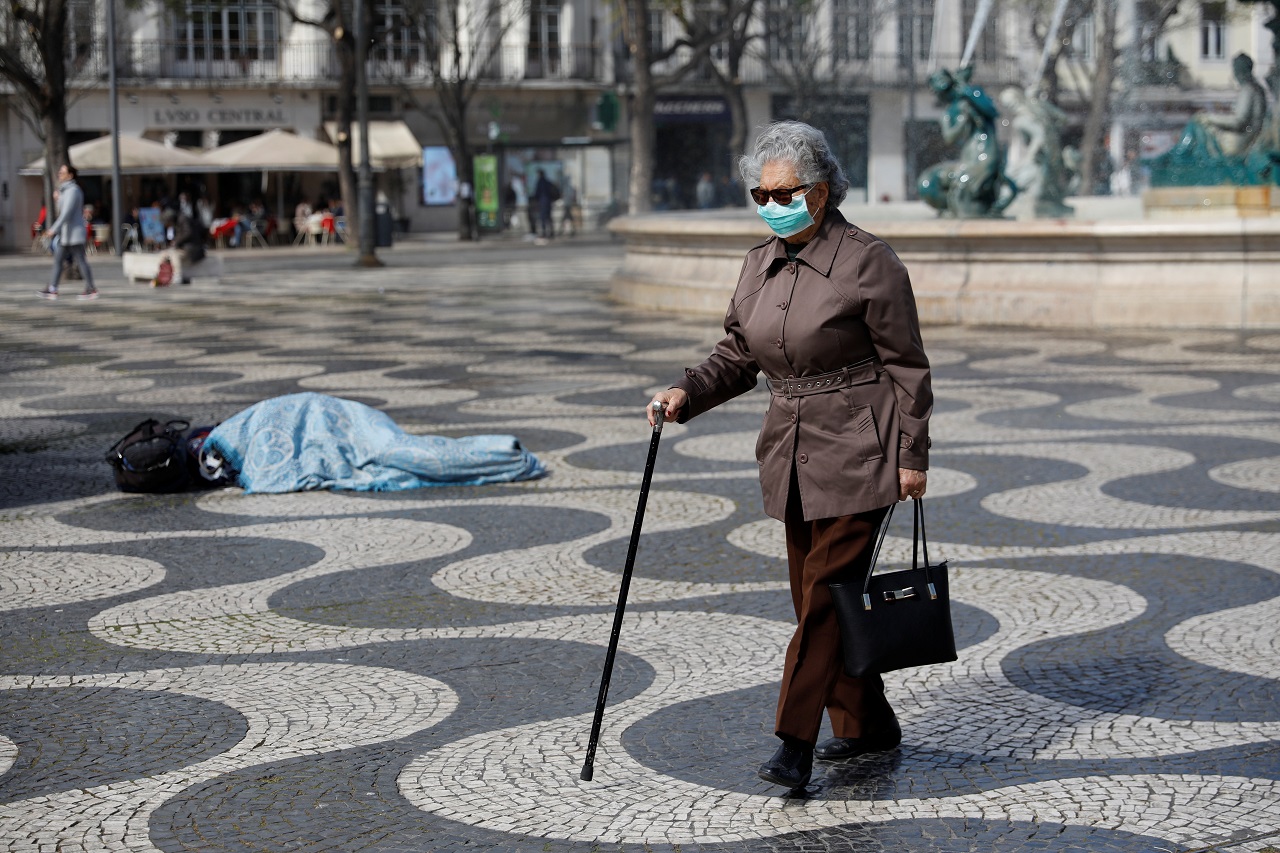 Idosa com máscara contra coronavírus caminha pela rua em Portugal 