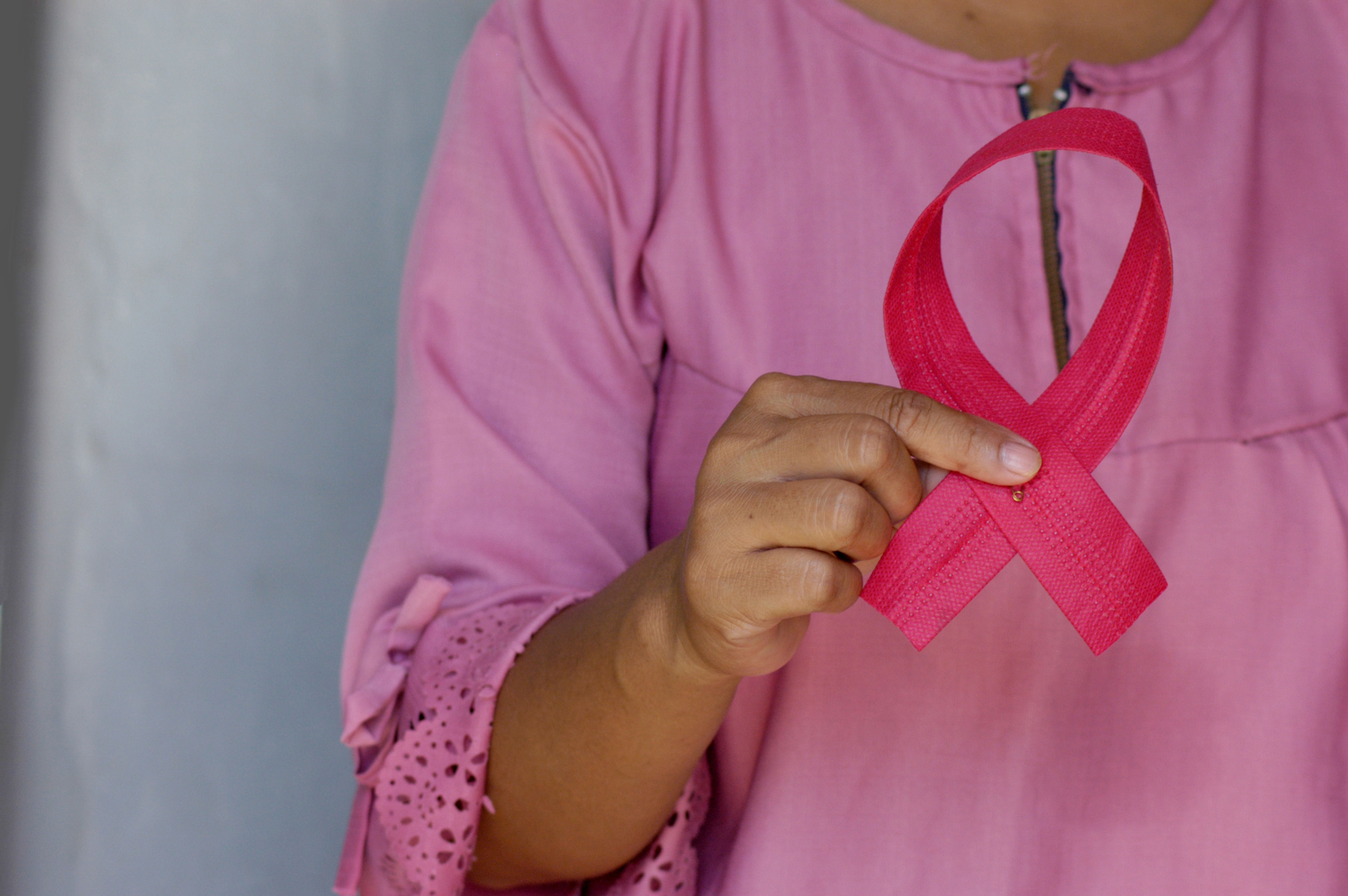 Mulher segura fita cor-de-rosa, símbolo da campanha Outubro Rosa