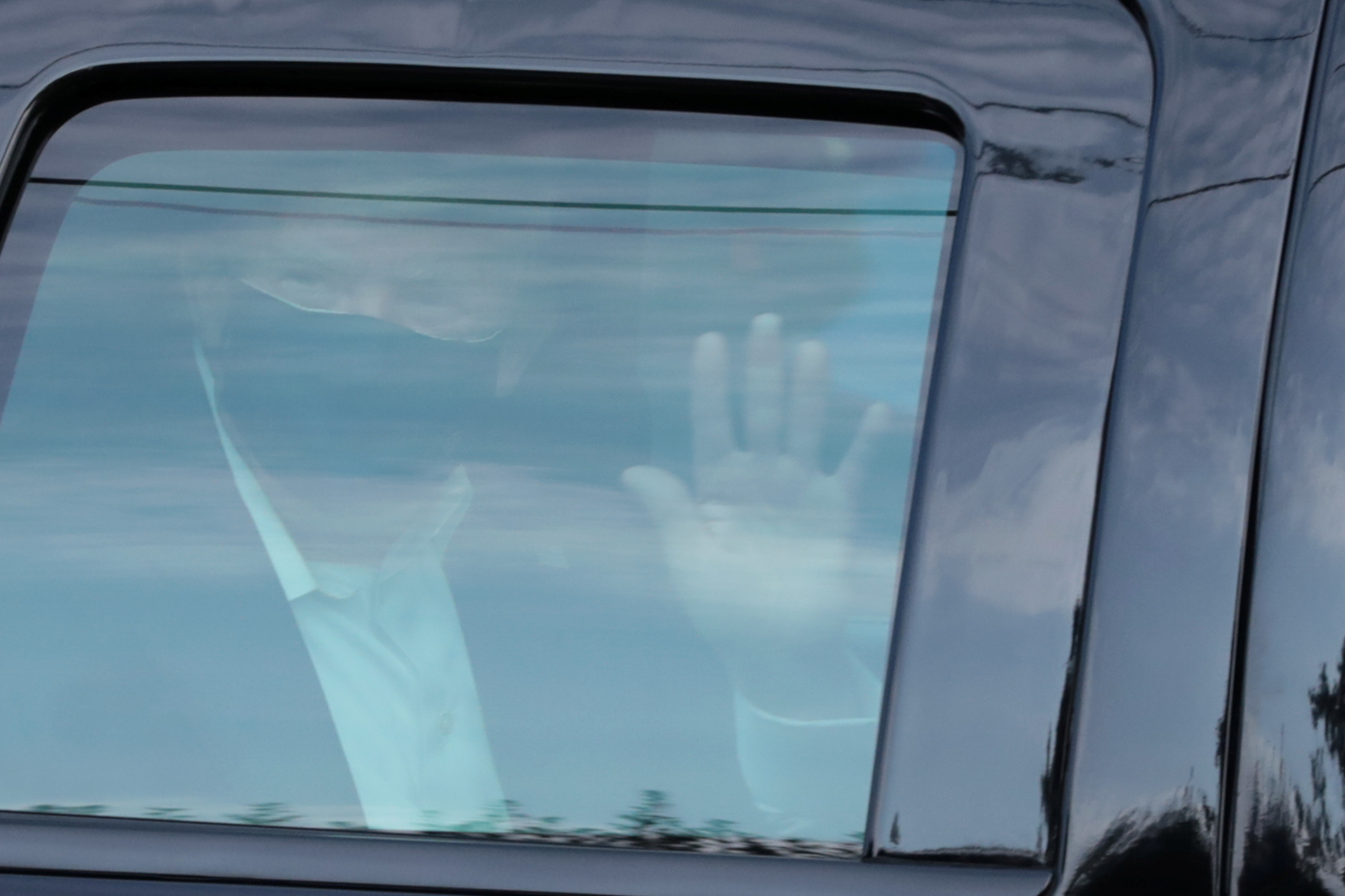 O presidente dos EUA, Donald Trump, acena de dentro de carro