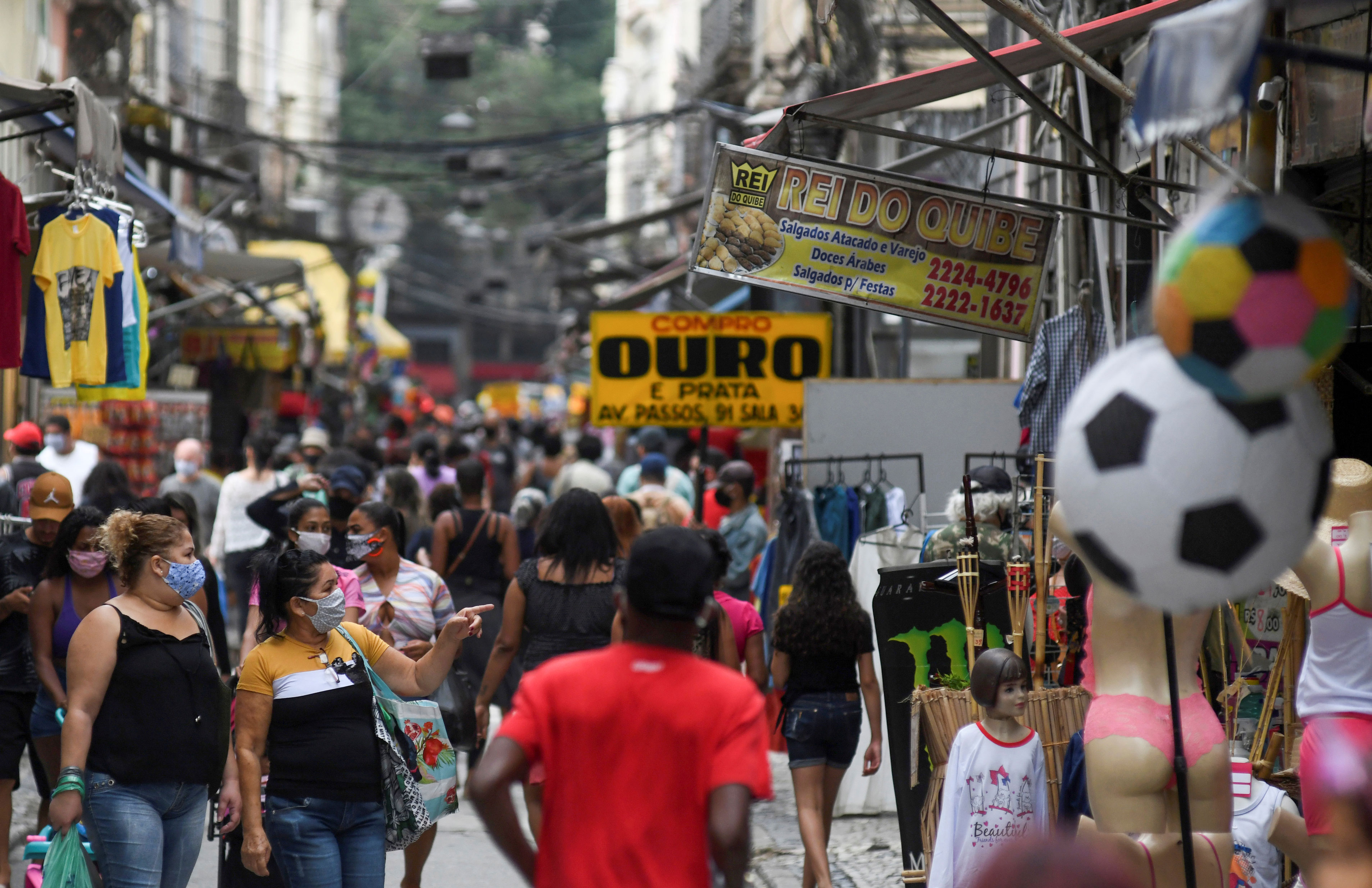 Pessoas caminham de máscara em rua comercial do Rio de Janeiro durante pandemia 