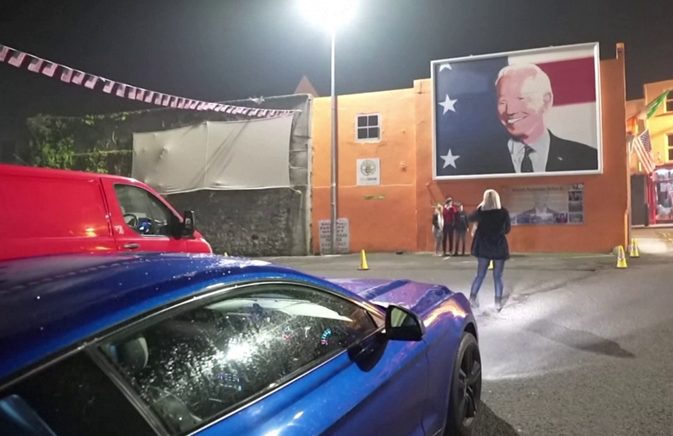 Moradores de Ballina, na Irlanda, tiram foto em frente a mural de Joe Biden