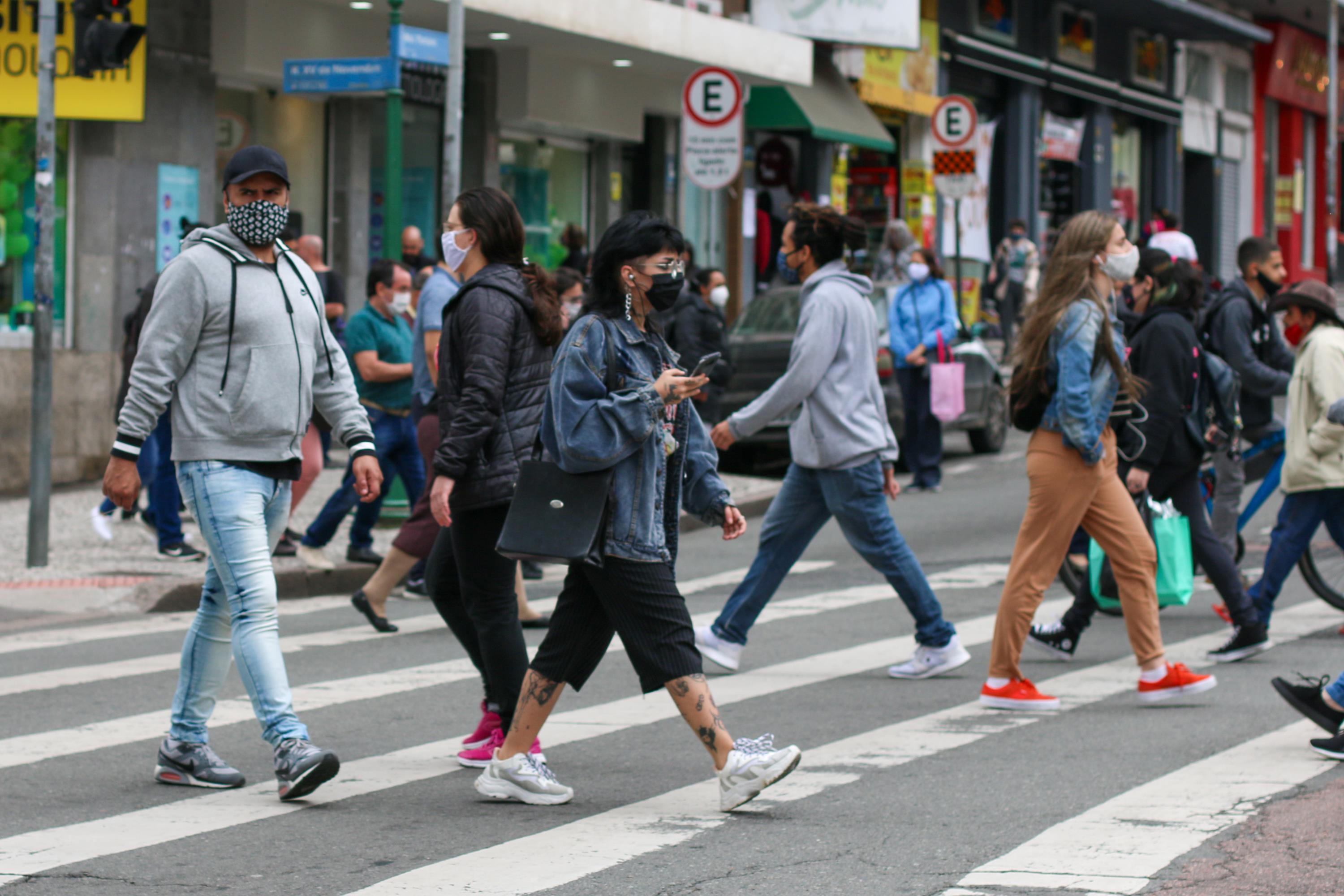 Pessoas caminham de máscara em Curitiba em meio à pandemia de Covid-19