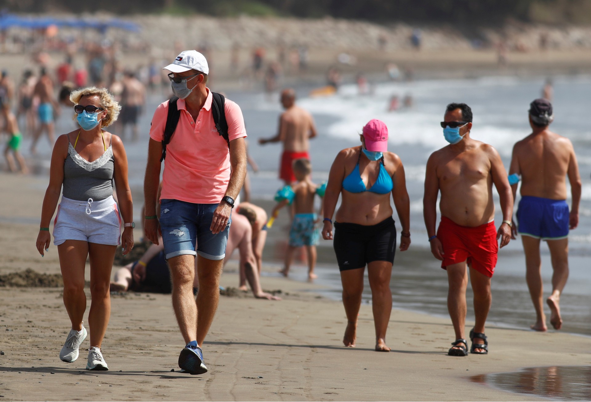 Pessoas caminham de máscara em praia das Ilhas Canárias