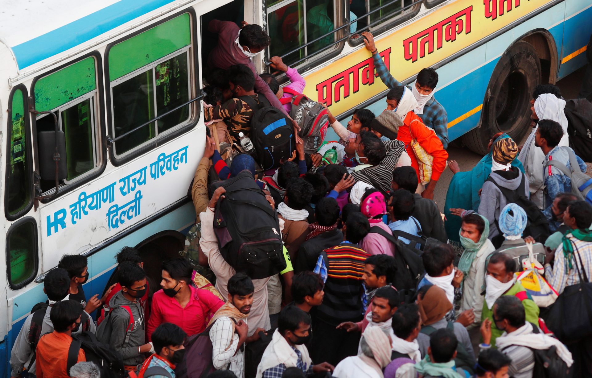 Trabalhadores migrantes tentam embarcar em ônibus e voltar ao interior da Índia