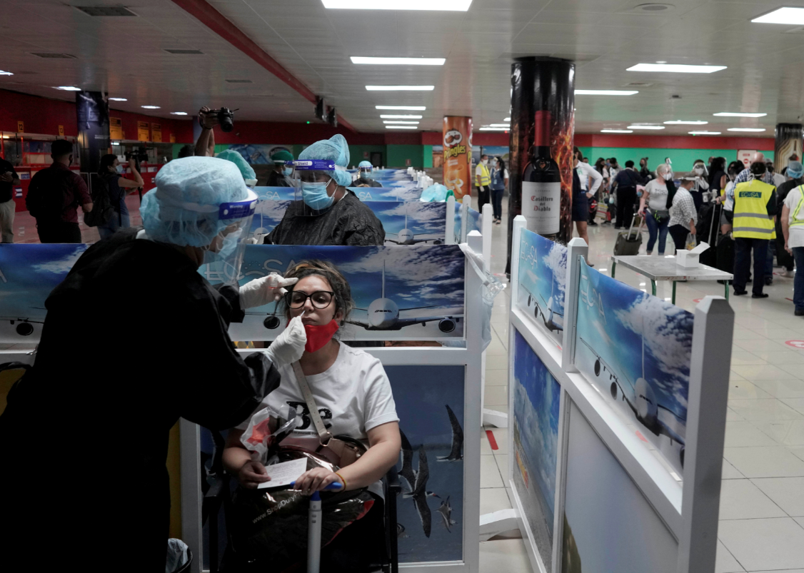 Profissional da saúde faz teste de Covid-19 em turista no aeroporto de Havana. 