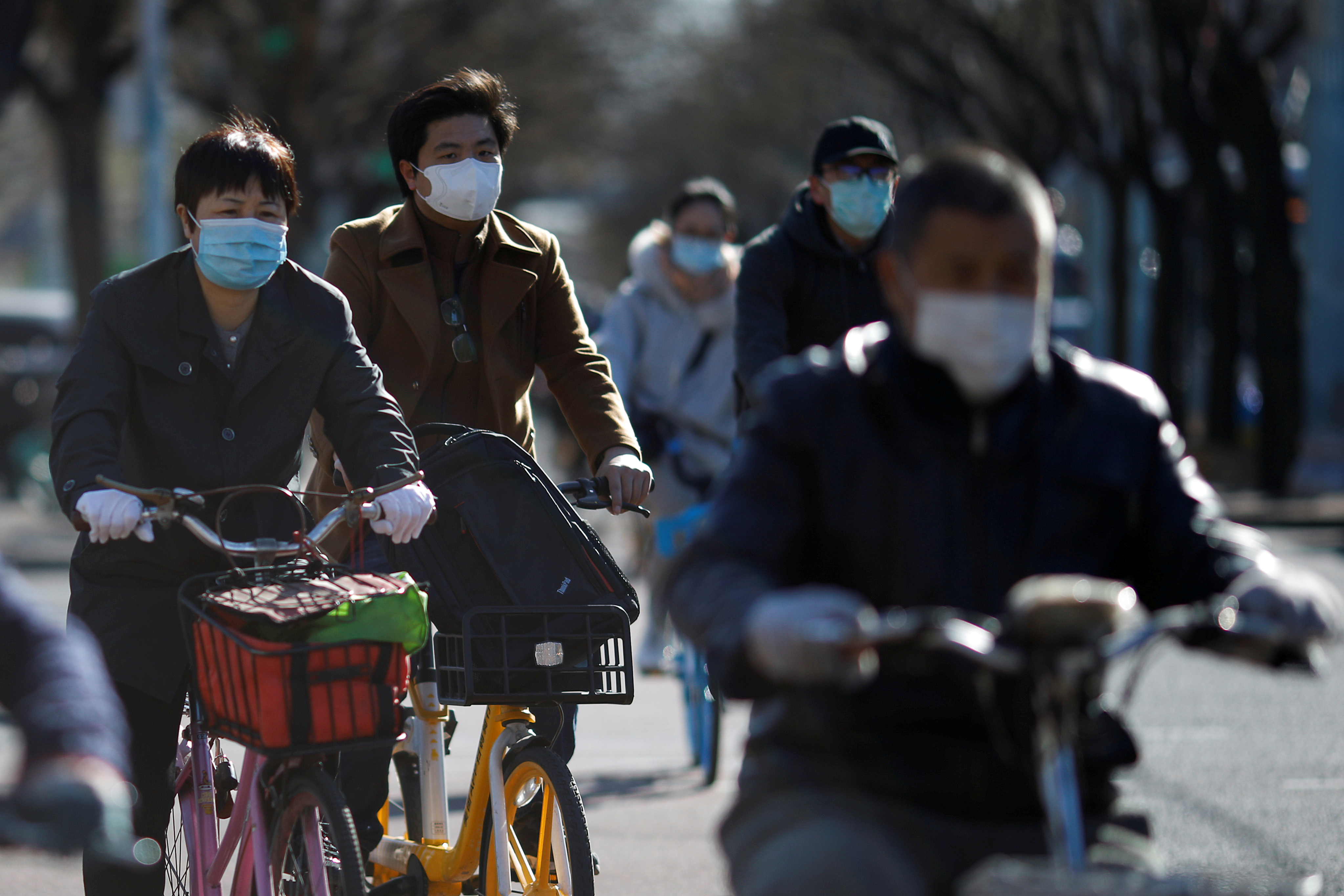 Pessoas usam máscaras para andar de bicicleta em Pequim