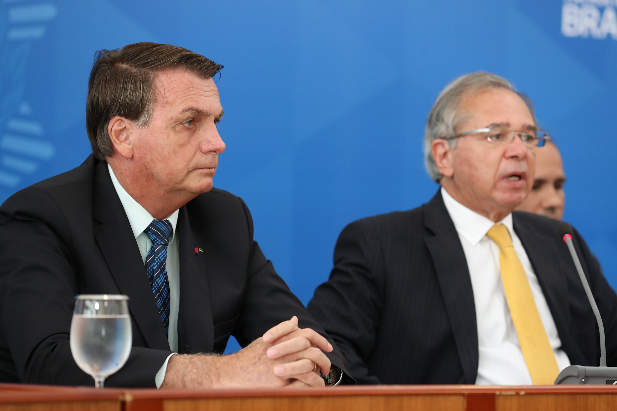 Ministro da Economia, Paulo Guedes, fala ao lado de Jair Bolsonaro durante colet