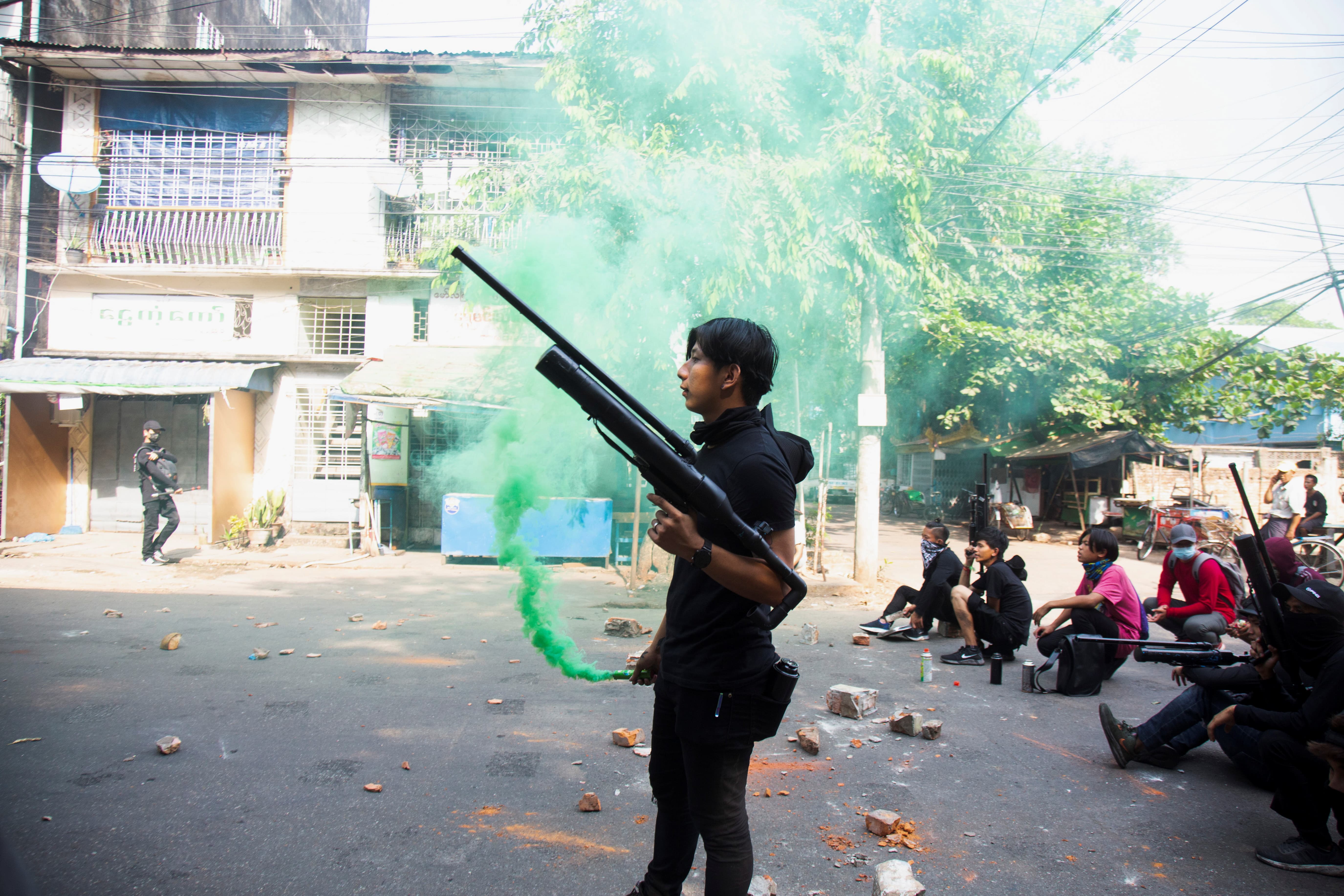 Manifestante segura arma feita com canos durante protesto em Mianmar