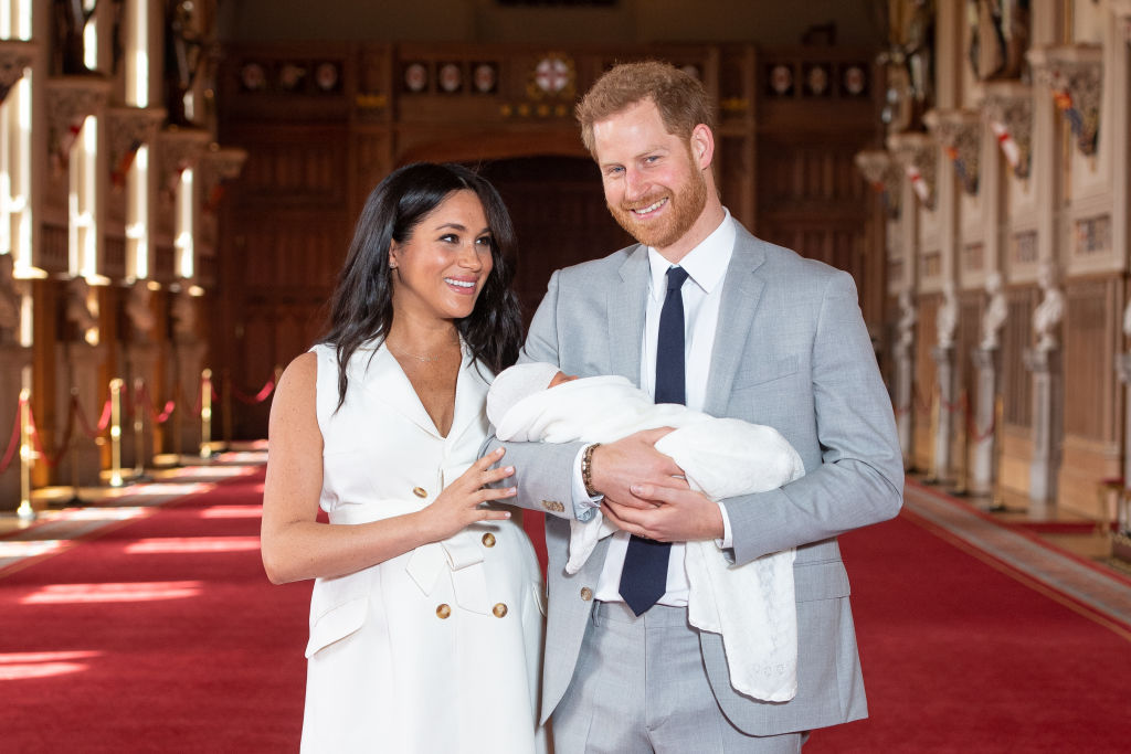 O príncipe Harry segura Archie Harrison ao lado de Meghan Markle