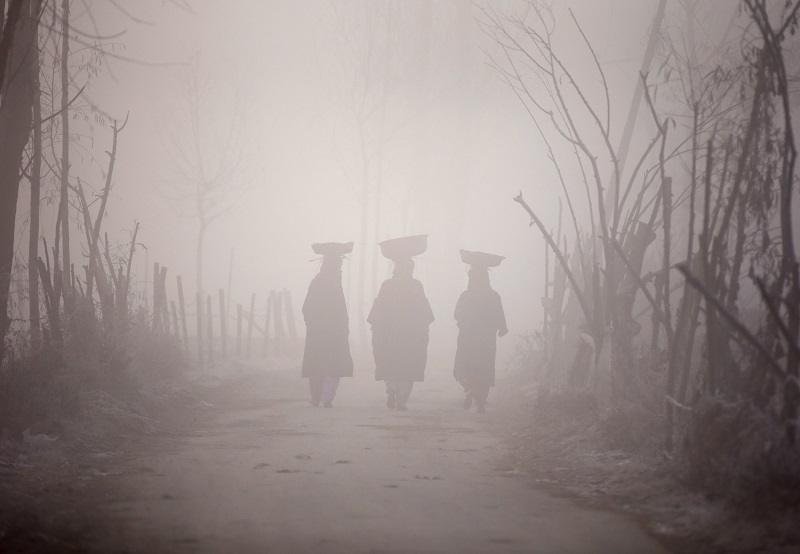 Mulheres caminham em meio à poluição do ar na Índia