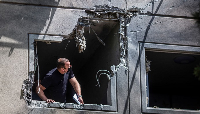 Um homem inspeciona uma janela destruída em uma casa atingida por um foguete 