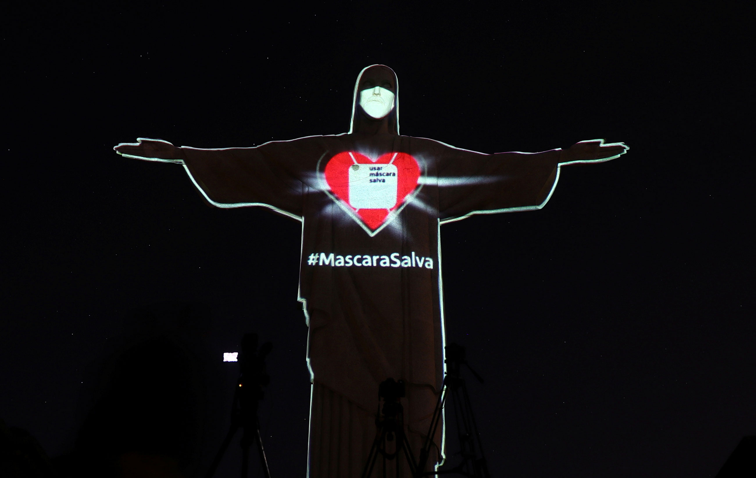 O Cristo Redentor, no Rio de Janeiro, iluminado com uma máscara sobre o rosto