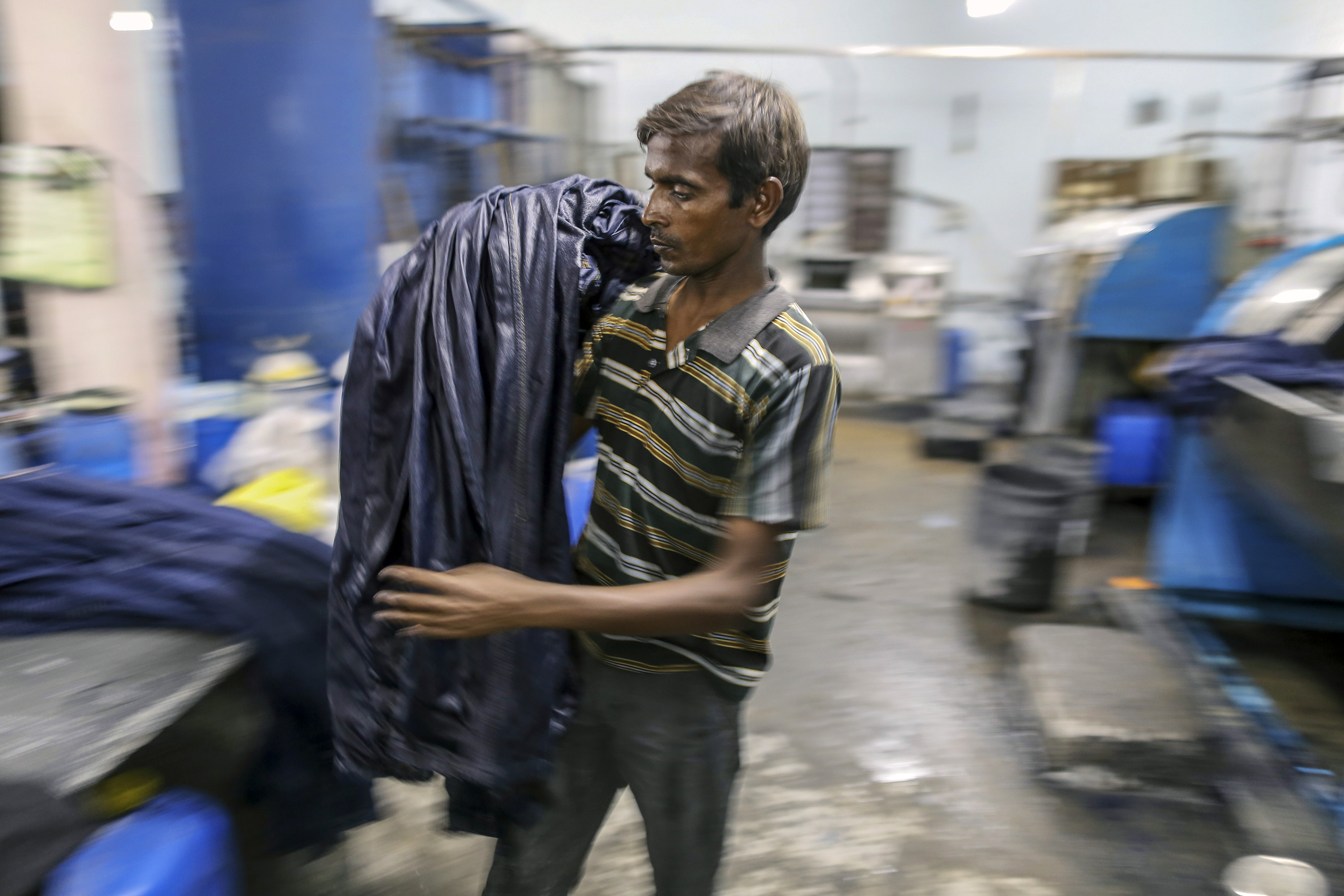 Funcionário descarrega jeans de uma máquina de tingimento na Índia