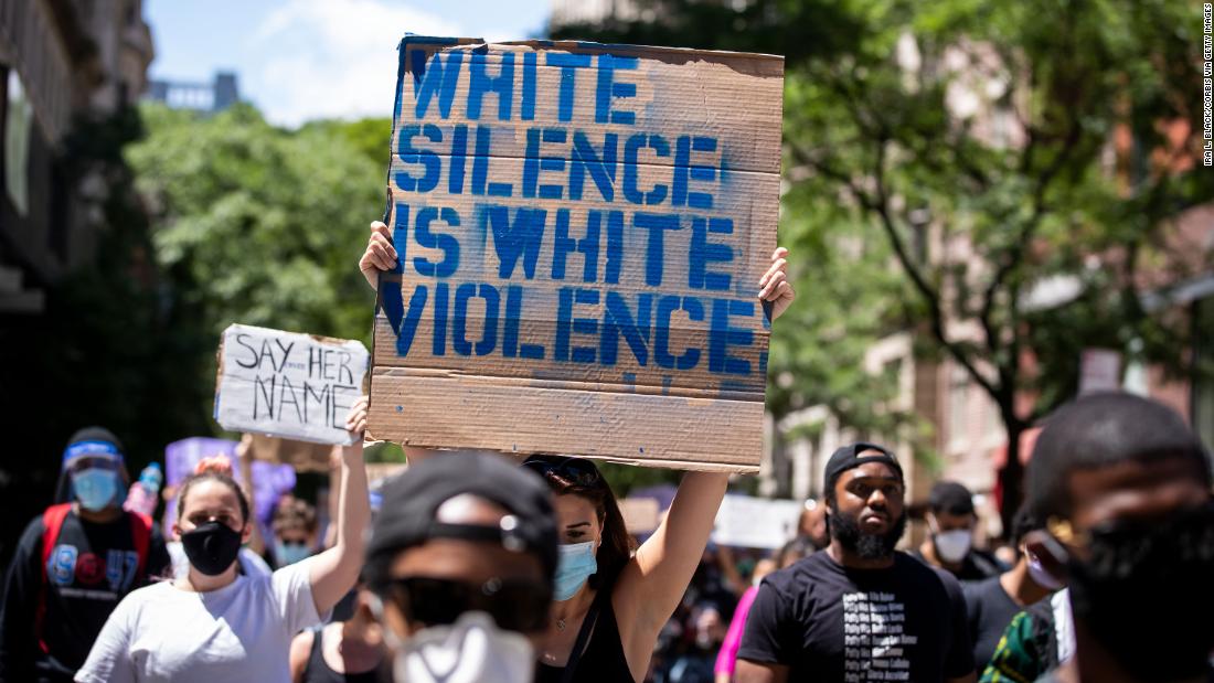 Manifestante segura cartaz que diz "O silêncio branco é uma violência branca".
