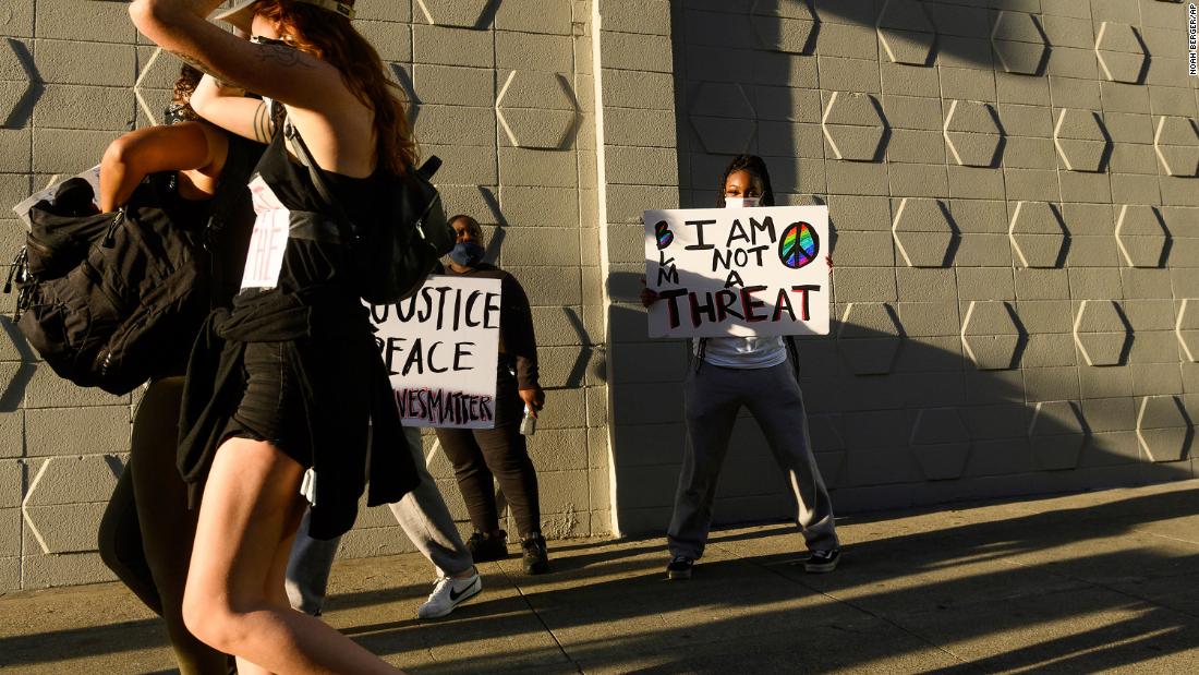 Mulher negra segura cartaz de protesto que diz "Eu não sou uma ameaça".