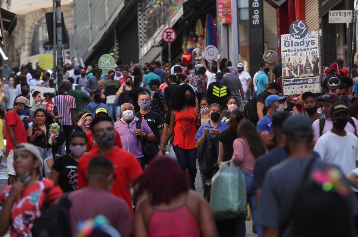 Pessoas caminham em rua comercial em São Paulo