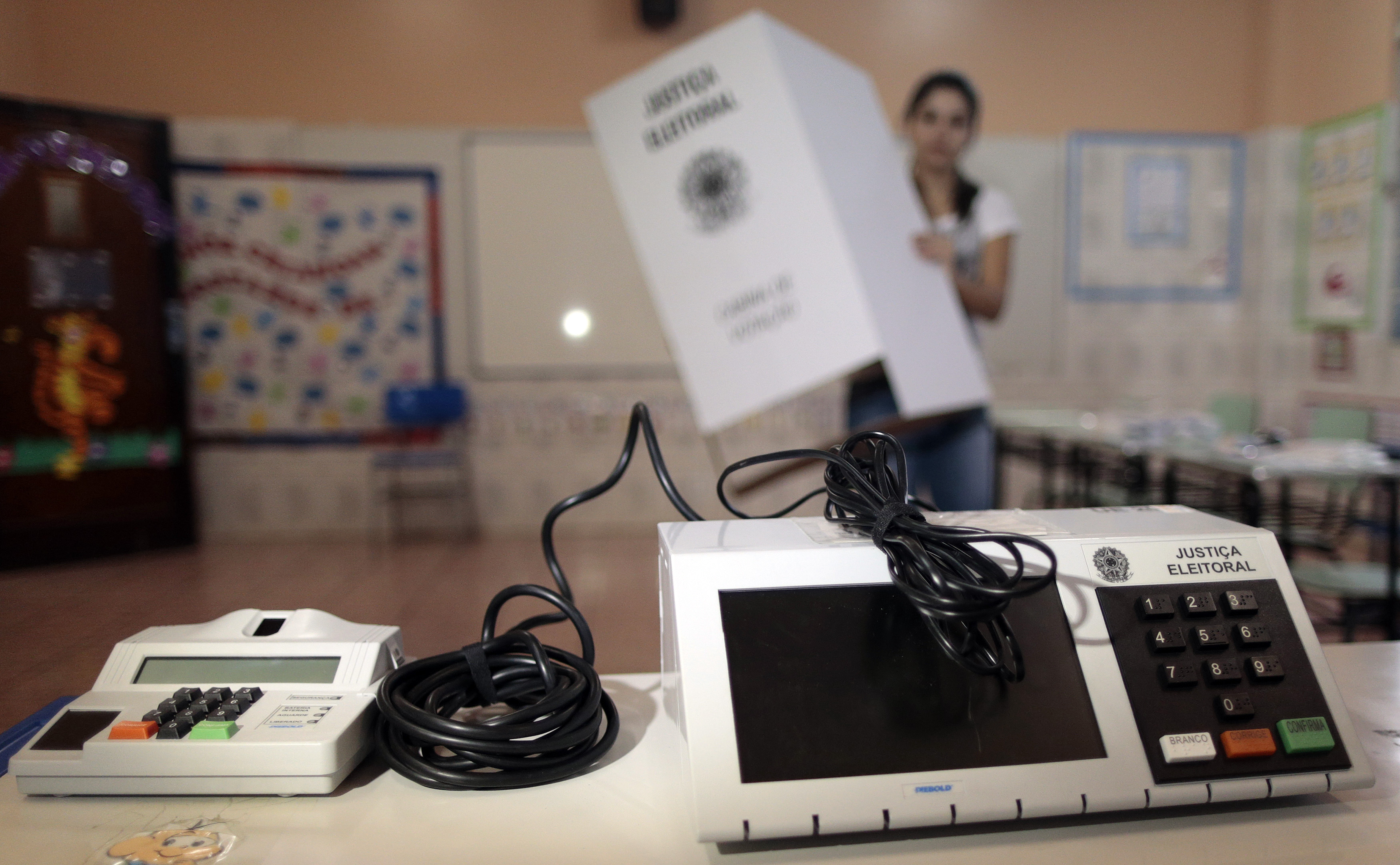 Funcionária da Justiça Eleitoral instala urna em local de votação