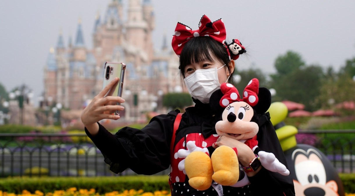 Visitante de parque da Disney tira selfie usando máscara de proteção: investidores gostaram do resultado