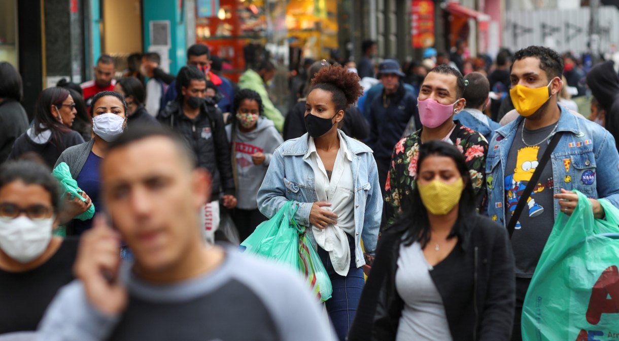 Pessoas com máscaras caminham em rua de comércio popular em São Paulo