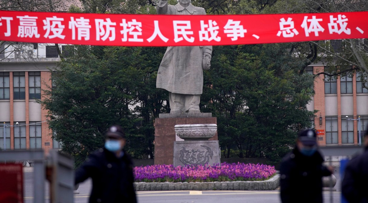 Guardas com máscara de proteção em frente a estátua de Mao Tse-Tung em Xangai