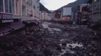 As enchentes causadas por chuvas excepcionalmente fortes arrastaram destroços e veículos ao longo de uma estrada