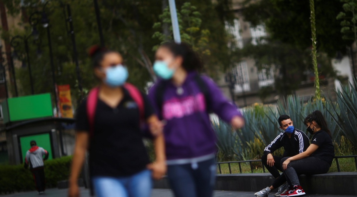 Pessoas utilizam máscara de proteção enquanto conversam em praça no México