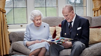 Palácio de Buckingham divulgou um foto da monarca e do marido sorridentes olhando um cartão feito pelos bisnetos