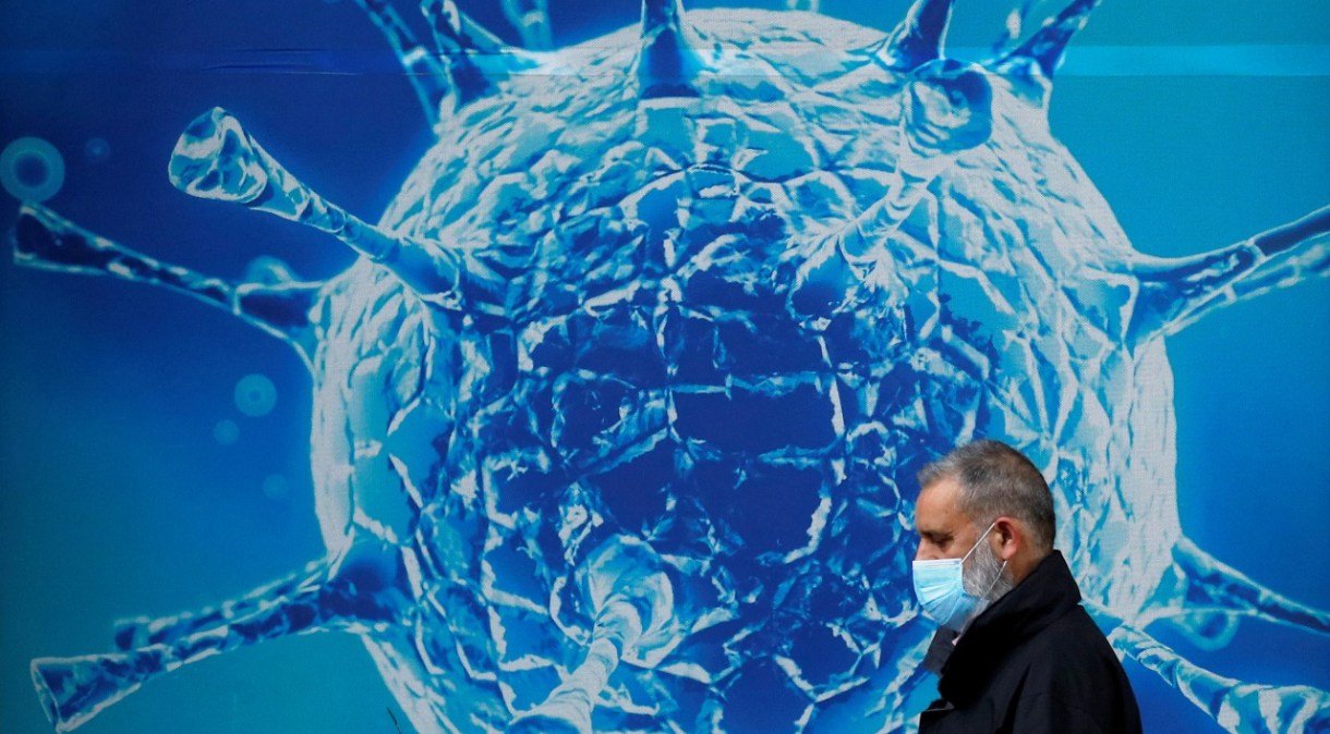 Homem passa em frente de ilustração de vírus em Oldham, Reino Unido