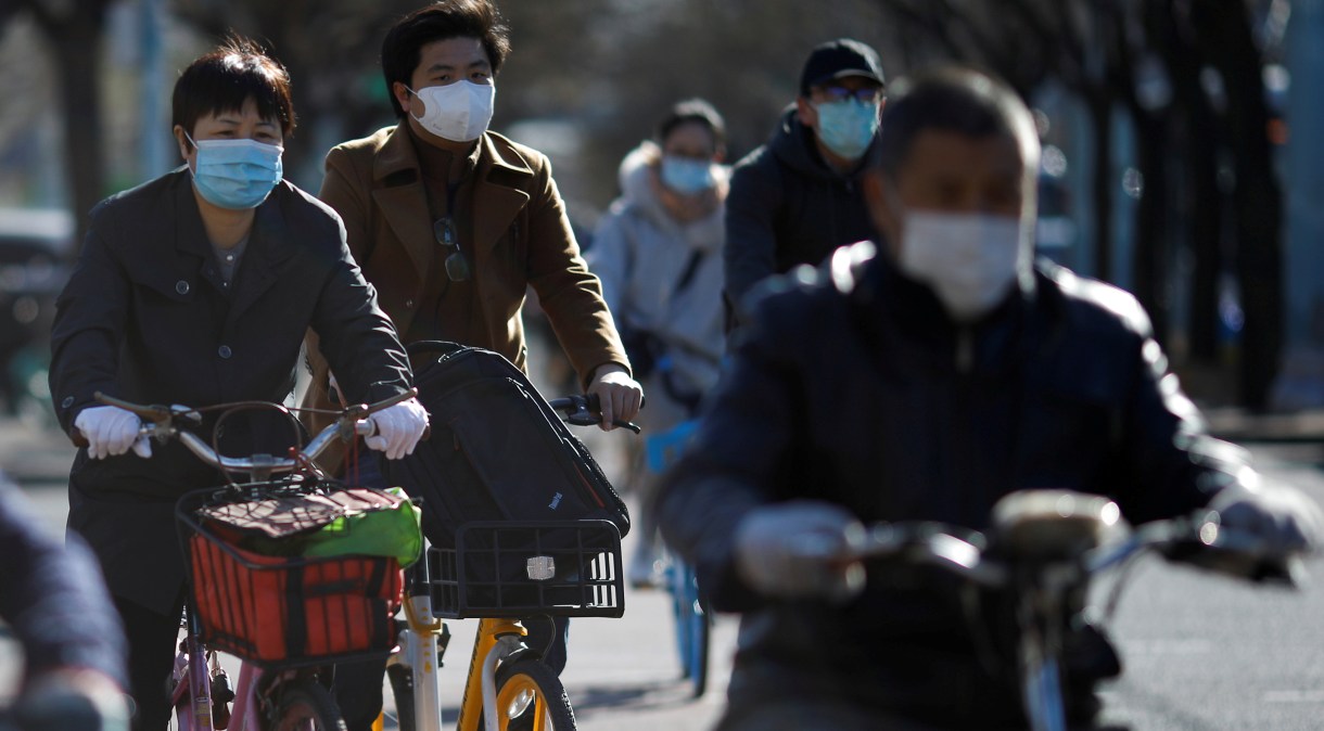 Pessoas usam máscaras para andar de bicicleta em Pequim em meio ao surto de COVID-19