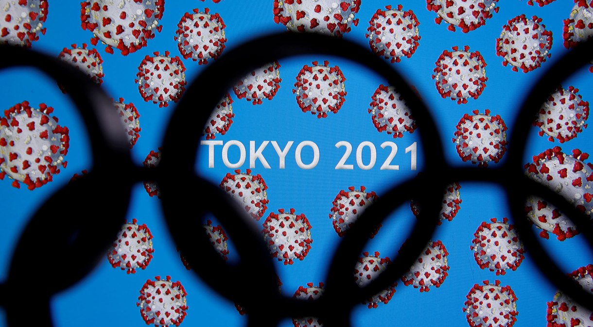 Arcos olímpicos na frente de painel anunciando adiamento dos Jogos de Tóquio para 2021