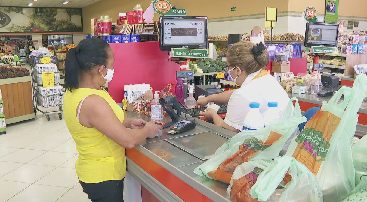 Consumir e caixa de supermercados usando máscaras de proteção contra a Covid-19