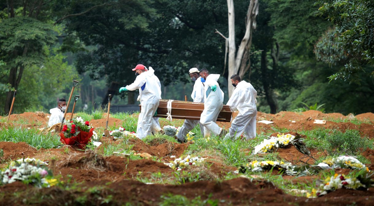 Funcionários do cemitério da Vila Formosa, em São Paulo, usam trajes de proteção ao carregar caixão de vítima da Covid-19