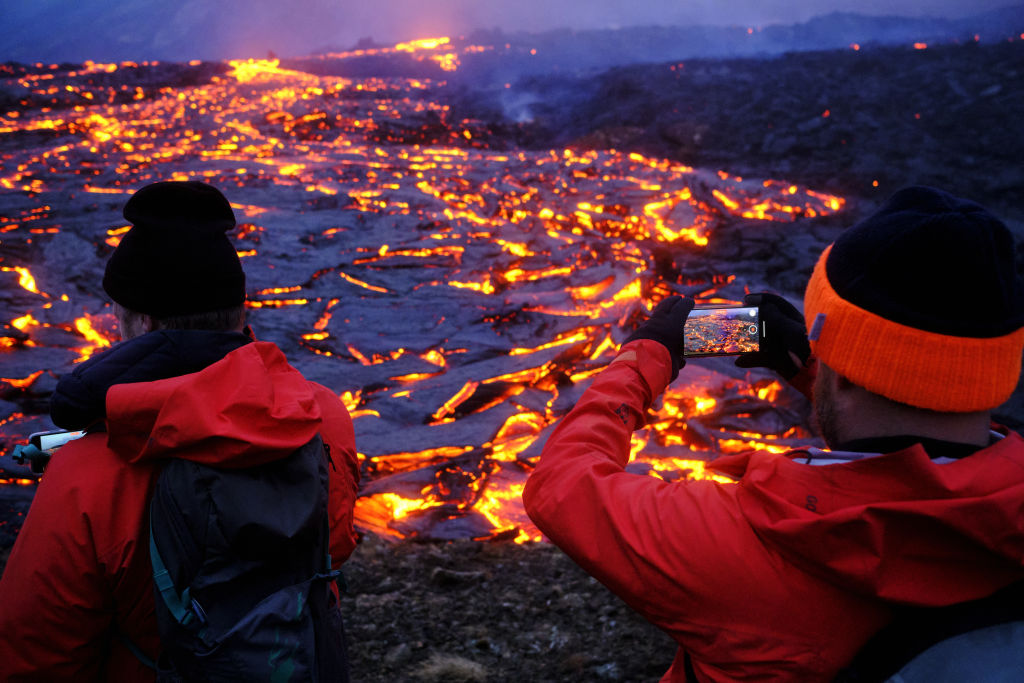 Turistas tiram foto perto da crosta de magma de vulcão na Islândia
