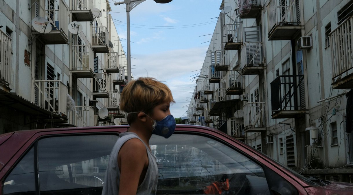 Menino usa máscara de proteção na favela de Manguinhos, no Rio de Janeiro