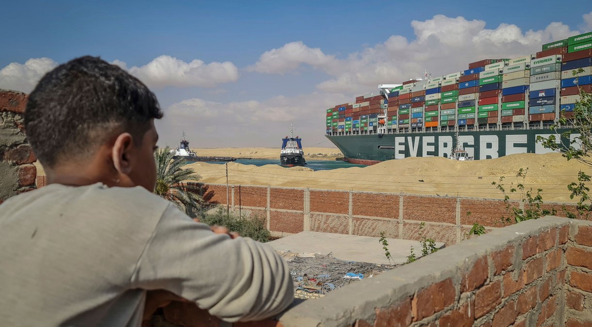 Garoto observa rebocadores tentarem desencalhar o navio Ever Given no canal de Suez