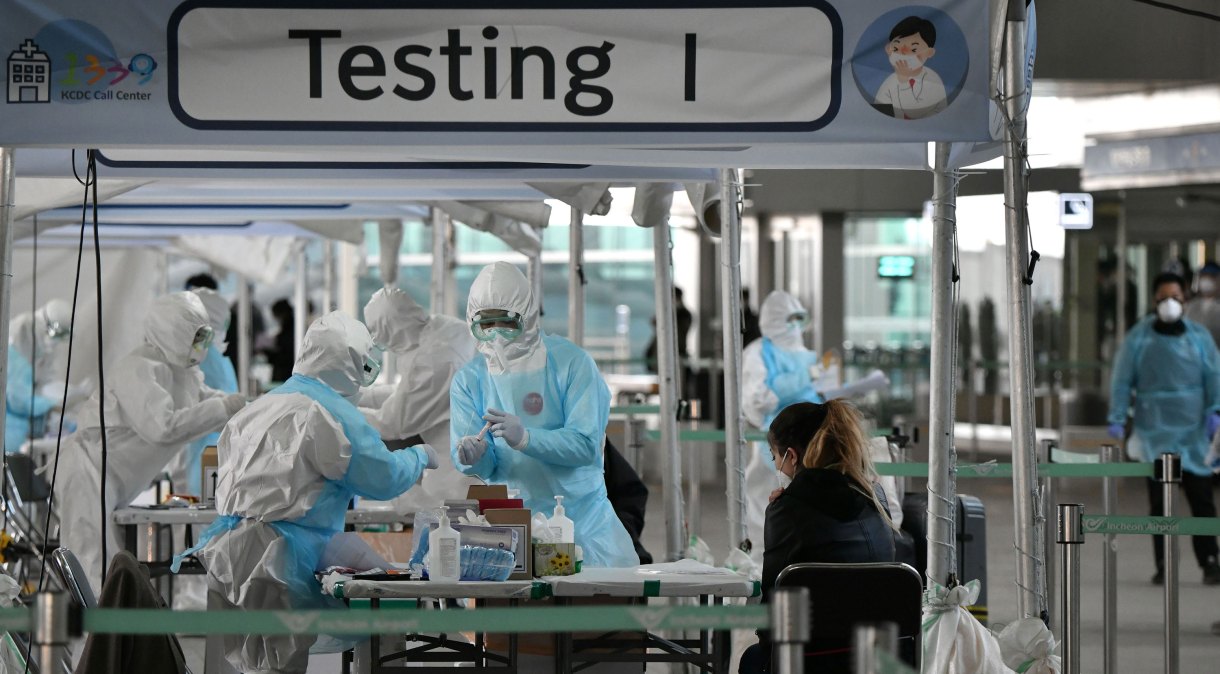Médicos usam roupa de proteção para coletar teste de coronavírus em aeroporto de Seul