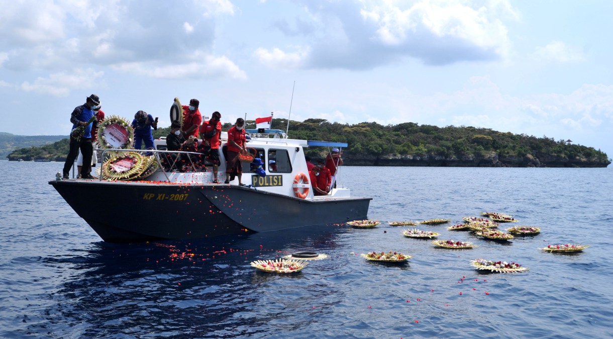 Pessoas jogam pétalas de flores com nomes dos marinheiros que morreram em submarino no litoral da Indonésia, em 26/04/2021
