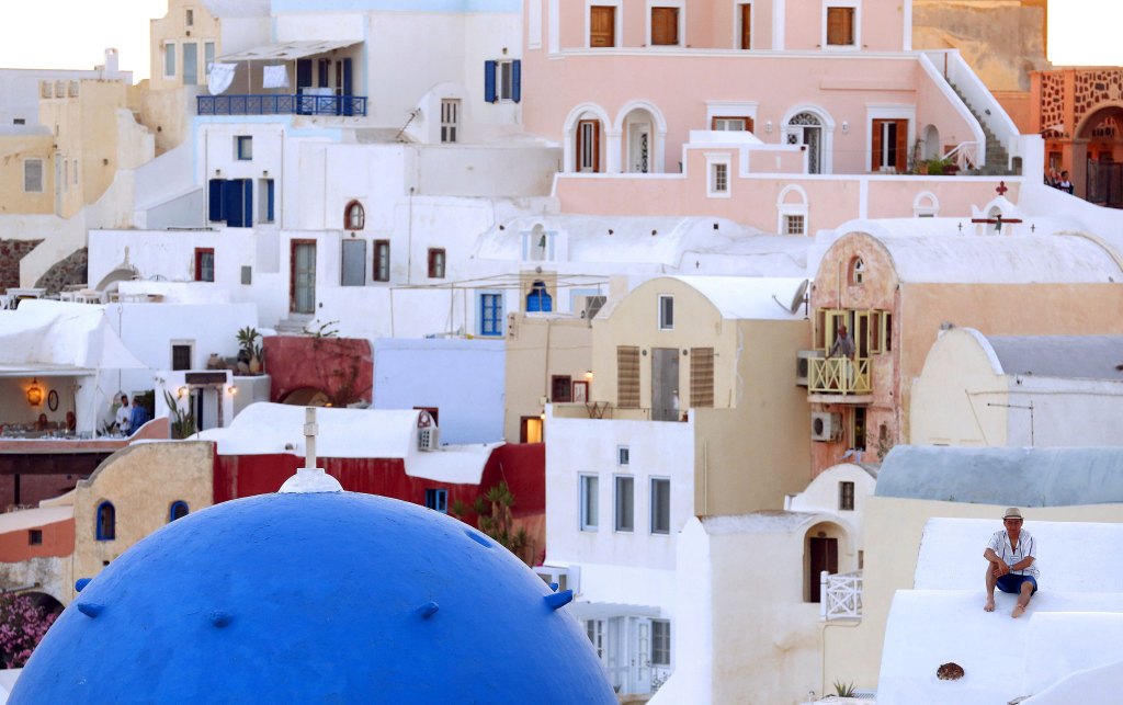 Homem assiste pôr-do-sol na ilha de Santorini, Grécia