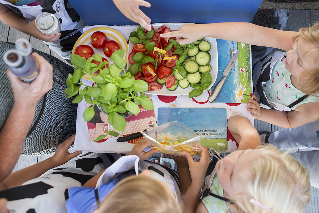 Crianças preparam salada em família/Getty Images