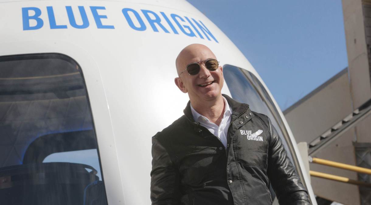 O bilionário Jeff Bezos em frente ao foguete de sua empresa de viagens espaciais, a Blue Origin