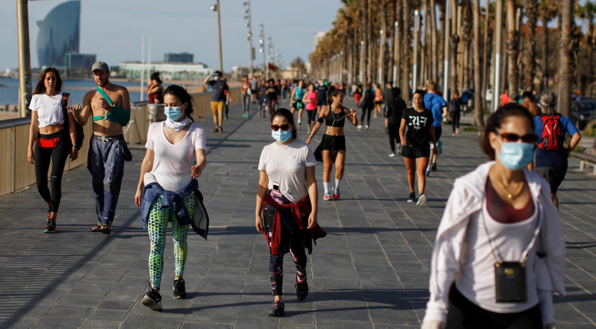 Pessoas caminham, se exercitam e tomam sol na orla em Barcelona, na Espanha