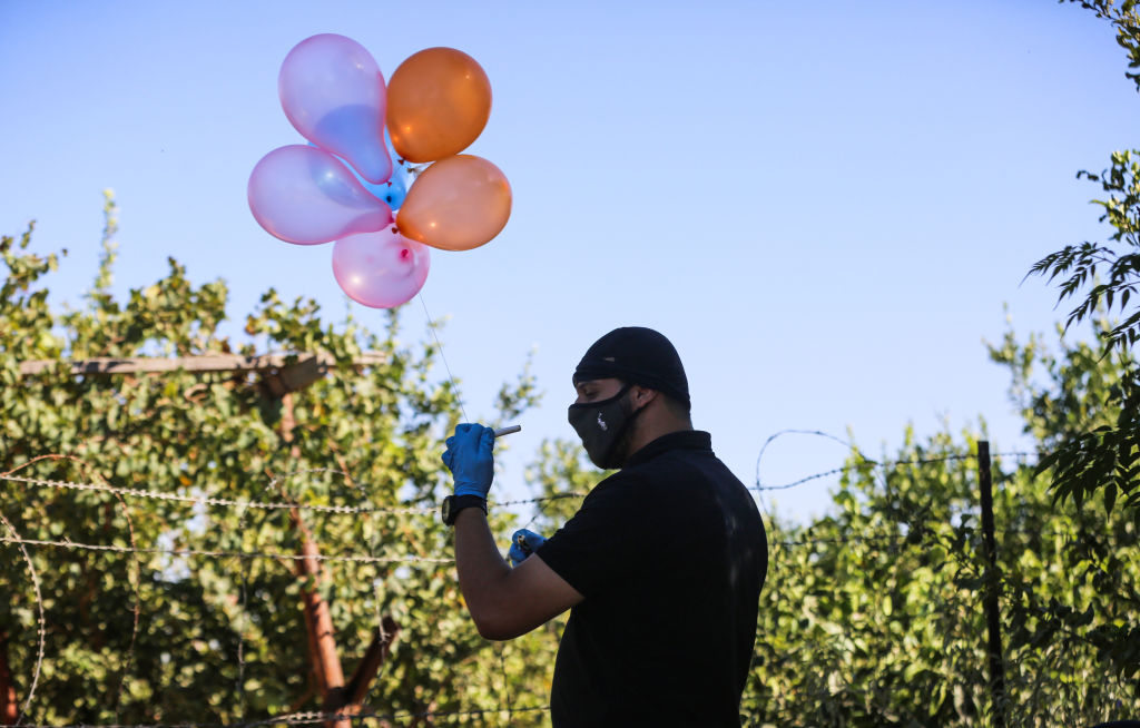 Homem palestino segura balão preso a explosivo nas proximidades do campo de refugiados de Jabalya